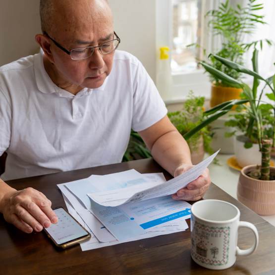 Man reading bills and using phone as calculator 