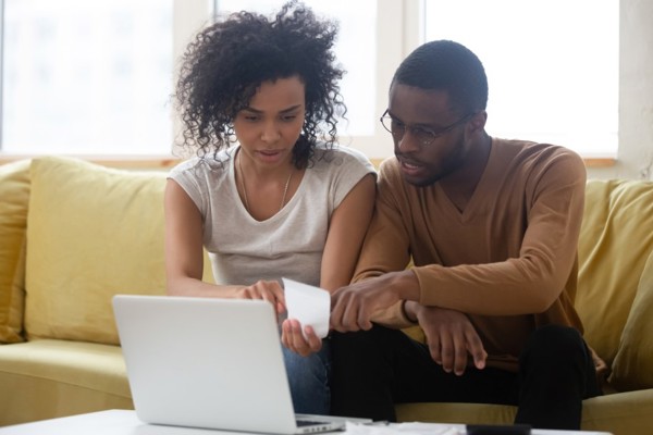 Couple look at a receipt in front of their laptop