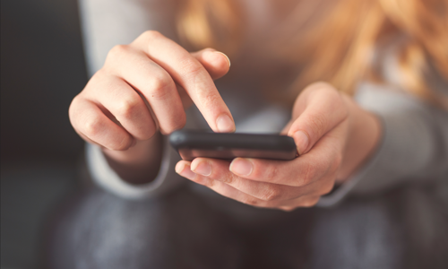 image: a woman looking at the Southern Housing website on her phone