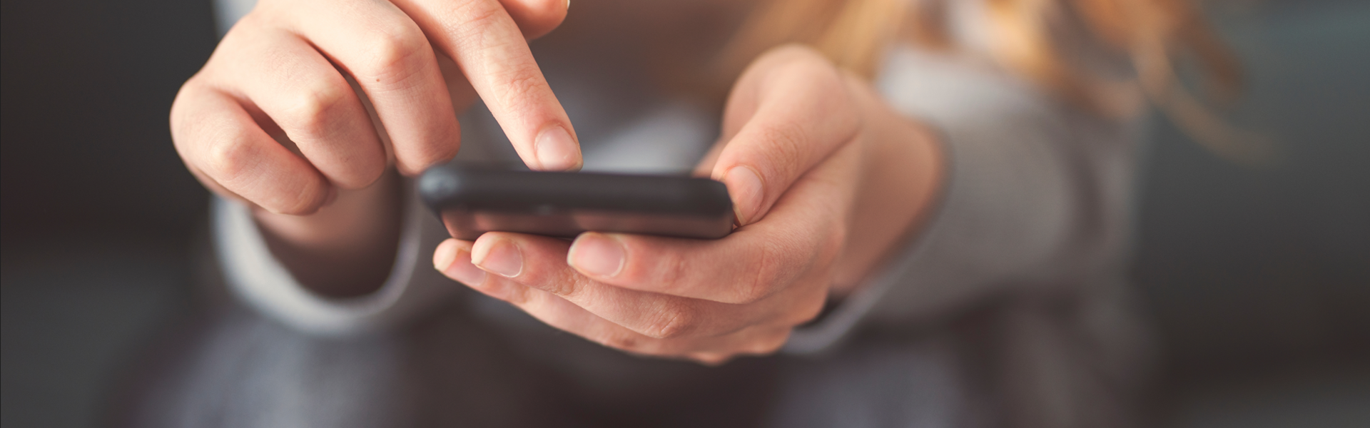 image: a woman looking at the Southern Housing website on her phone