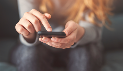 image: a woman looking at the Southern Housing website on her phone
